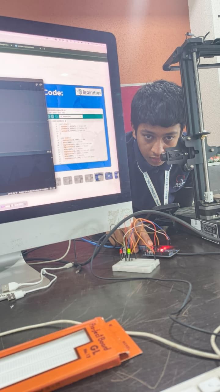 Student building an Arduino circuit alongside a 3D printer